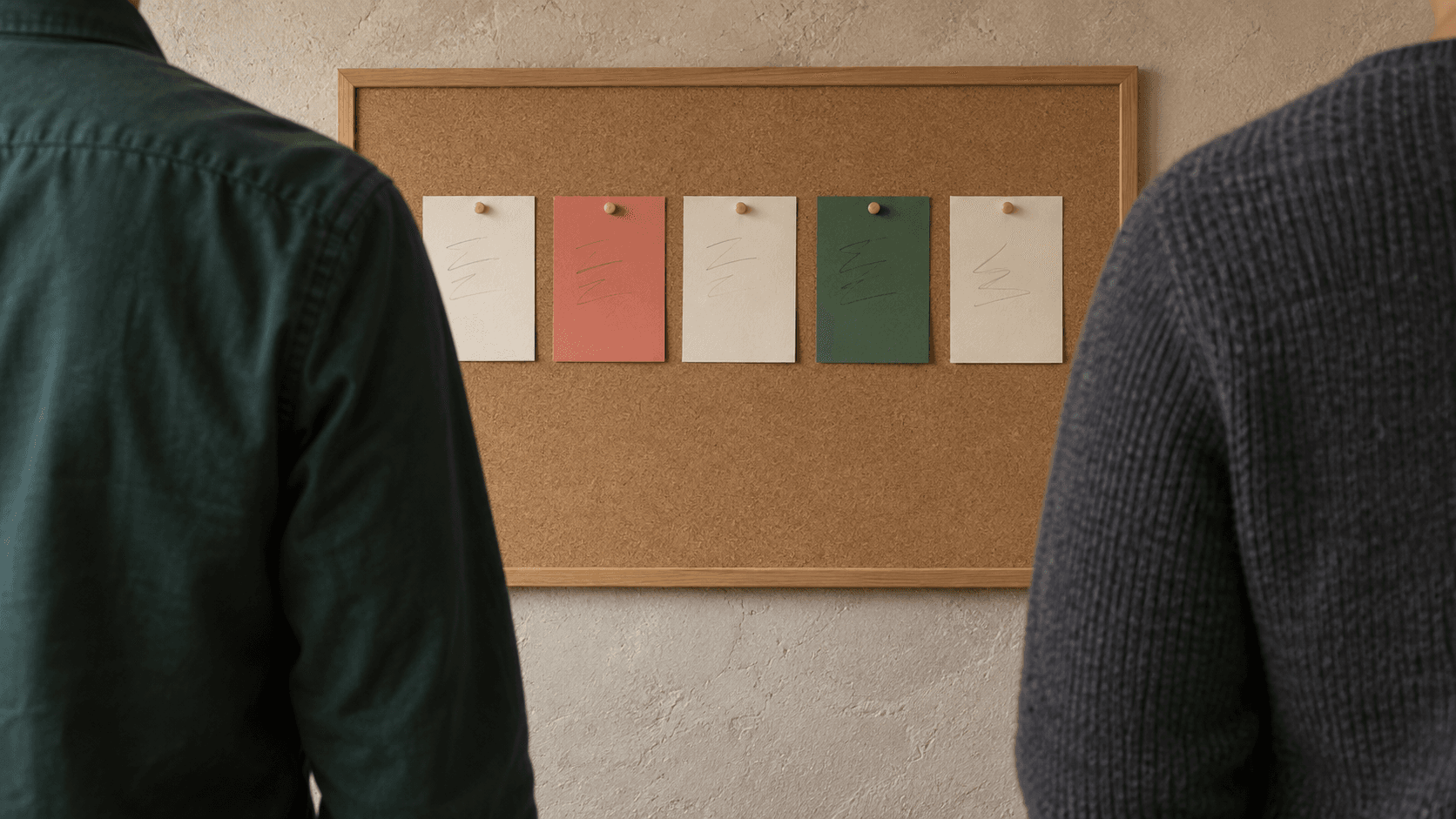 Twee collega's bekijken van achteren een fysiek bord met vijf workflowkaarten; gezichten en handen blijven buiten beeld.